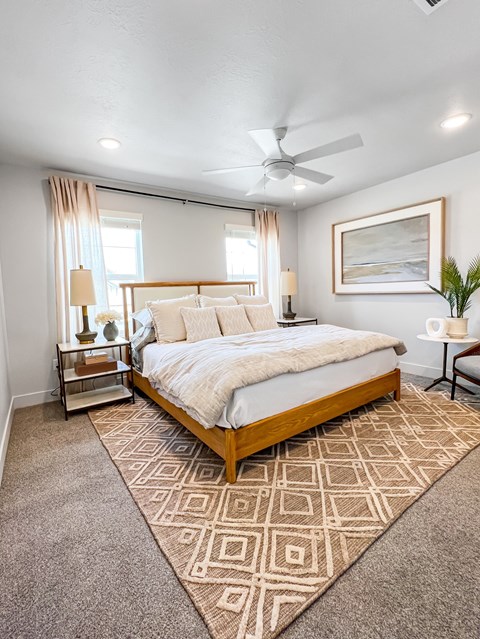 A bedroom with a large bed and a ceiling fan.