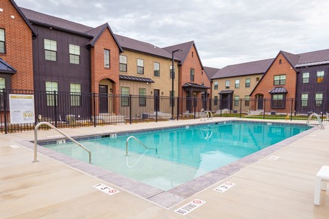 A swimming pool in front of a row of houses.