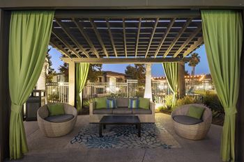 a patio with green curtains and a couch and a table