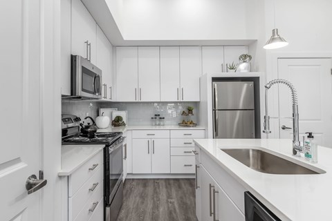 A modern kitchen with white cabinets and stainless steel appliances.
