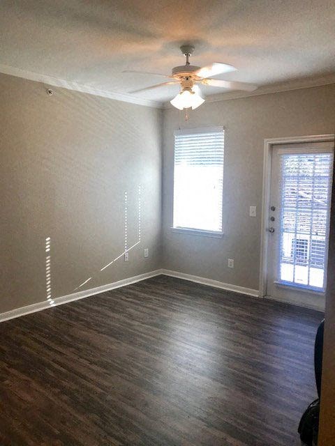 an empty living room with a ceiling fan and a window