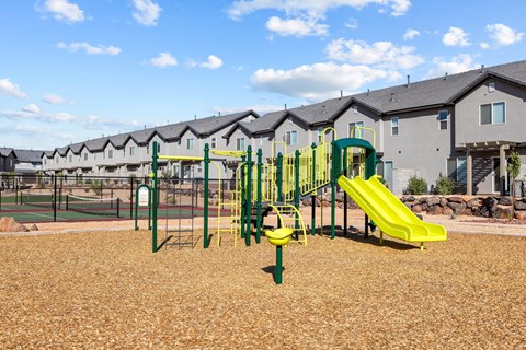 a playground with yellow and green equipment in front of apartments