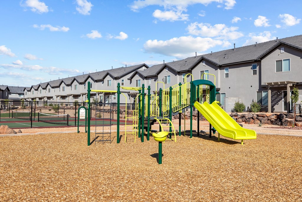 a playground with yellow and green equipment in front of apartments