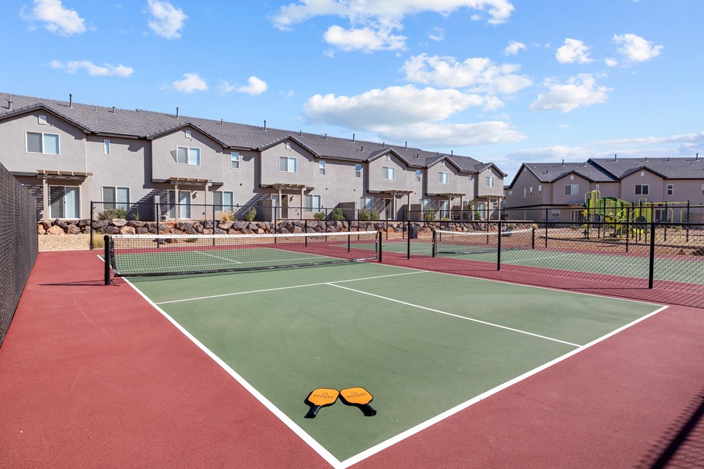 a tennis court with apartments in the background