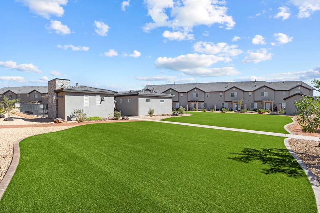a green lawn in front of a row of apartment buildings