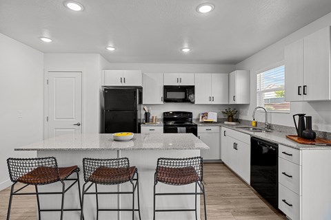 a kitchen with white cabinets and a counter top with three stools