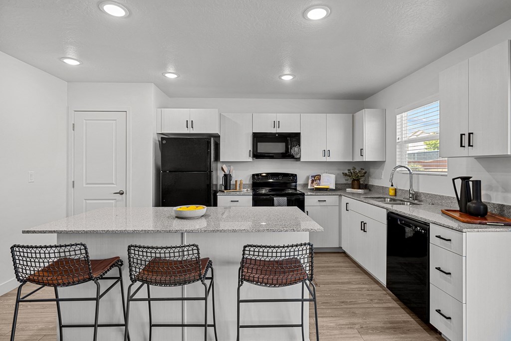 a kitchen with white cabinets and a counter top with three stools