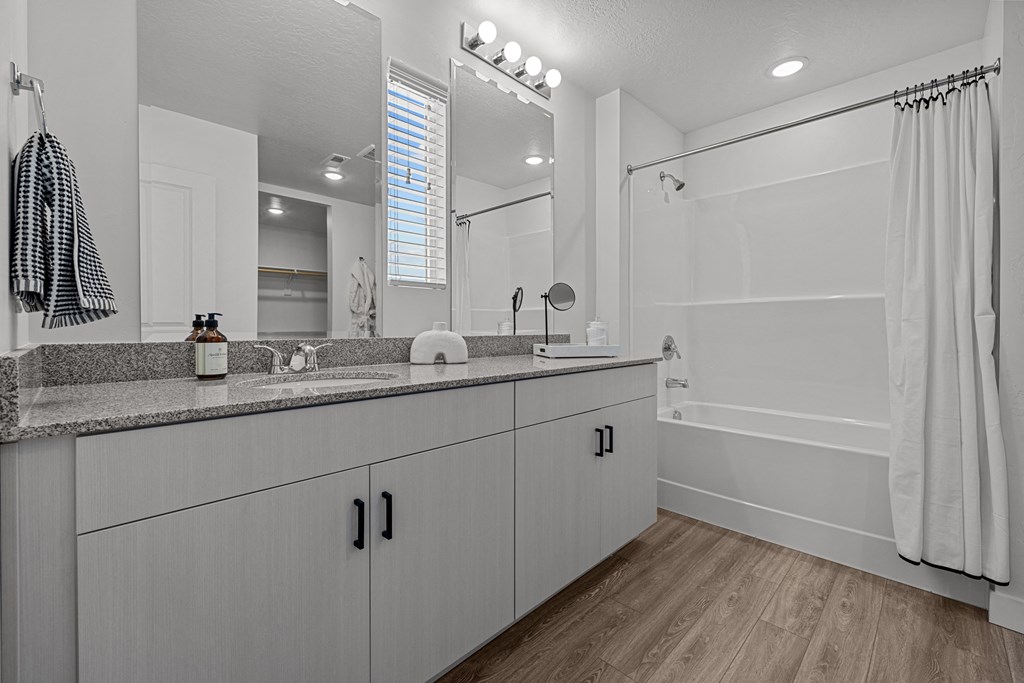 a bathroom with white cabinets and a large mirror and a shower