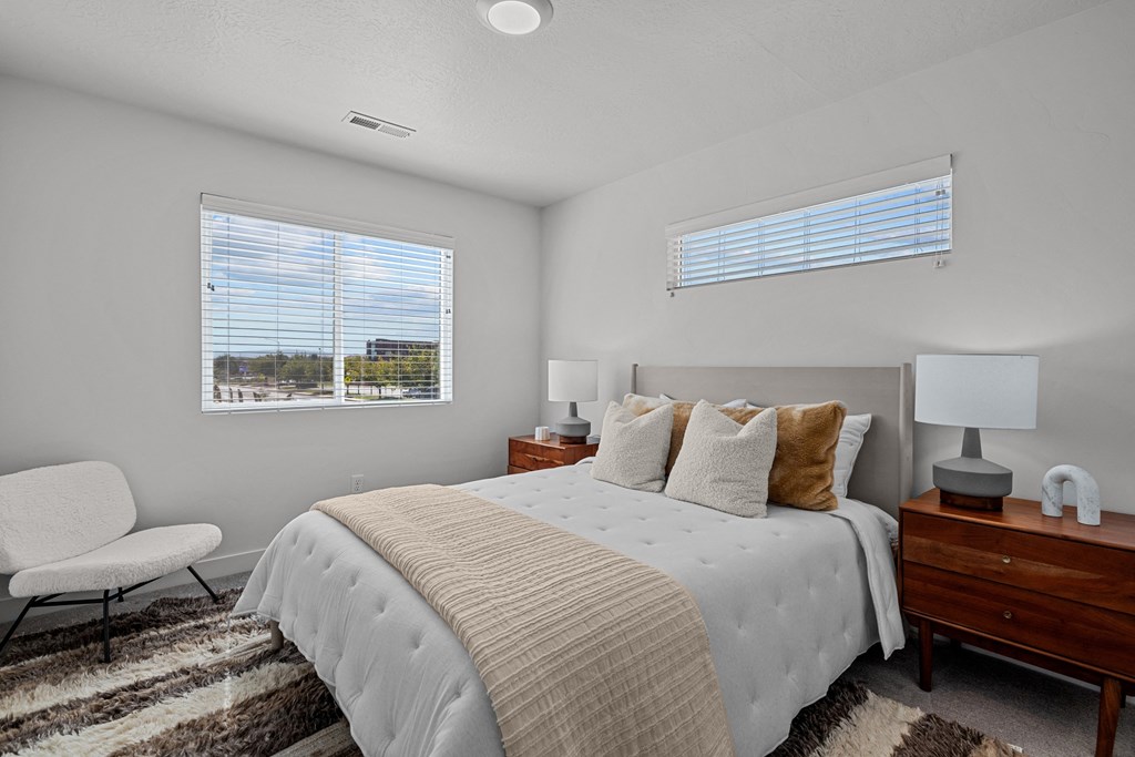 a bedroom with a large bed and two windows