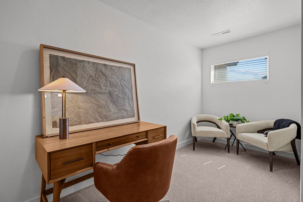 the living room has two chairs and a desk with a lamp and a table with