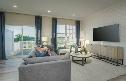 A modern living room with a grey sofa and a flat screen TV mounted on the wall.
