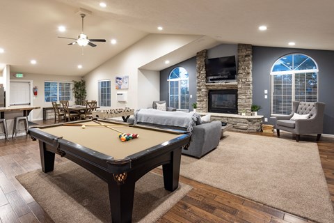A pool table is in the middle of a room with a fireplace and a couch.
