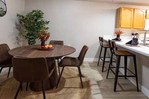 A kitchen with a round wooden table surrounded by brown chairs.