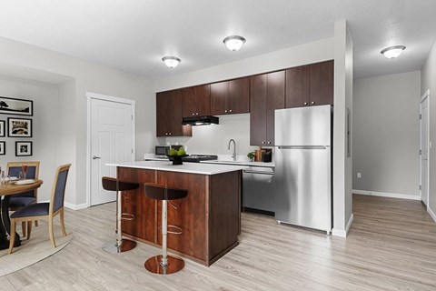 Element 170 Apartments Beaverton   A kitchen with a refrigerator, sink, and bar stools.