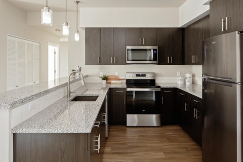a modern kitchen with granite counter tops and dark wood cabinets