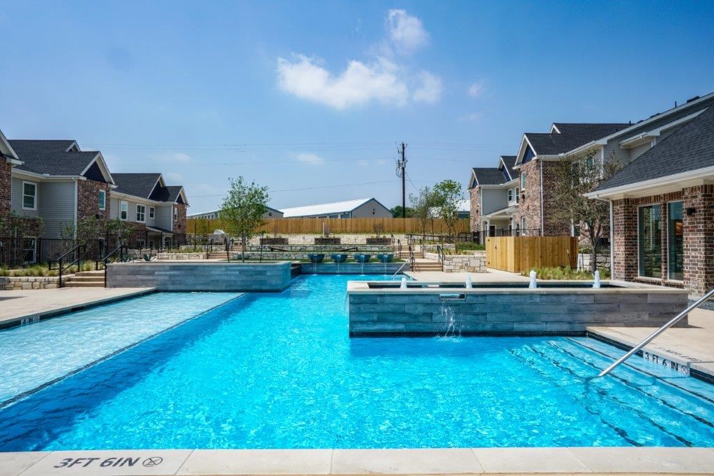 A swimming pool in a residential area with houses in the background.