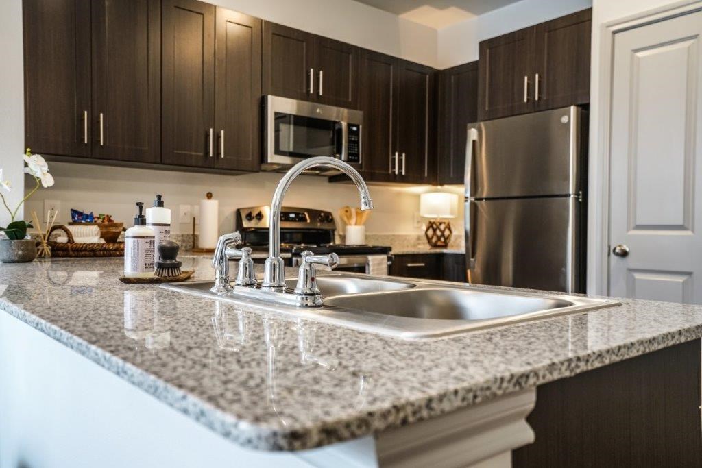 A kitchen with a granite countertop and stainless steel appliances.