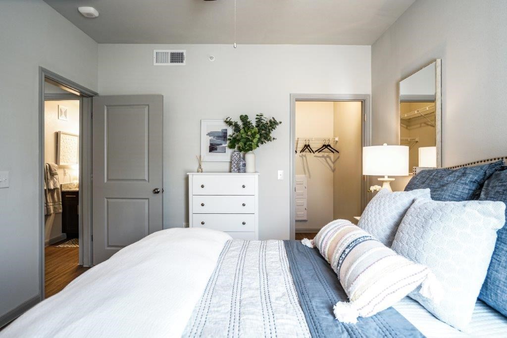 A bedroom with a large bed and a white dresser.