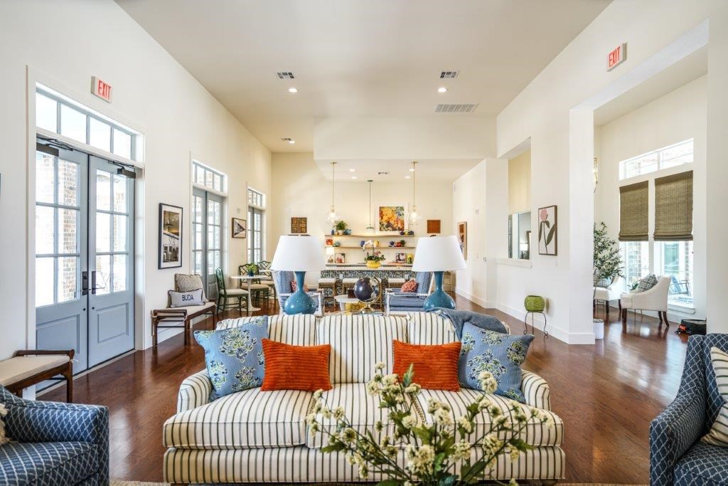 A living room with a striped couch and a vase of flowers on it.
