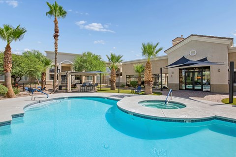 A swimming pool surrounded by palm trees and a building in the background.