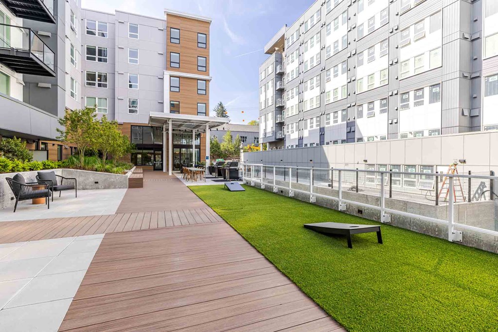 A long wooden walkway leads to a building with a grassy area on the right.