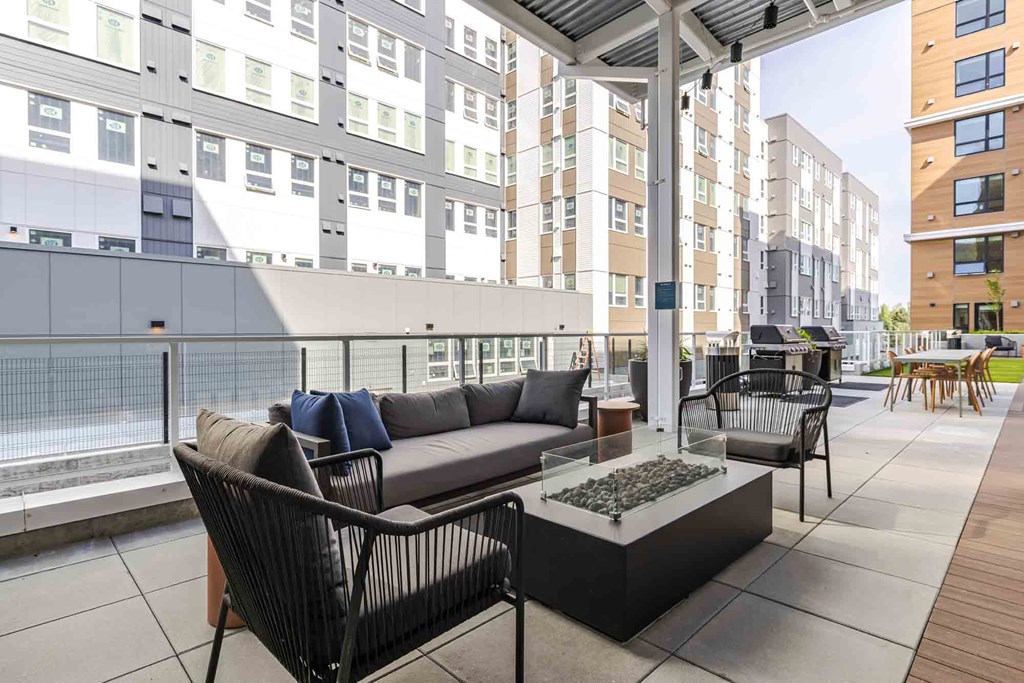 A patio with a couch, chairs, and a table with a fire pit.