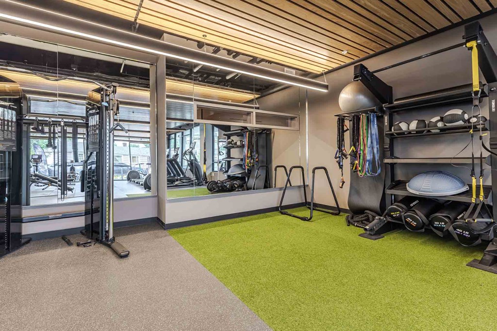 A gym with a green floor mat and a variety of exercise equipment.