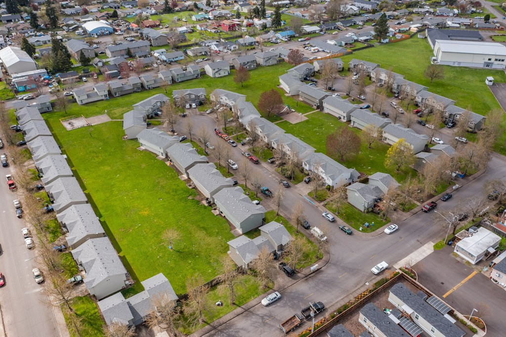 an aerial view of a neighborhood with green grass and cars parked on the street