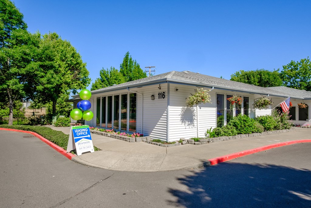 a white building with a sign and balloons in front of it