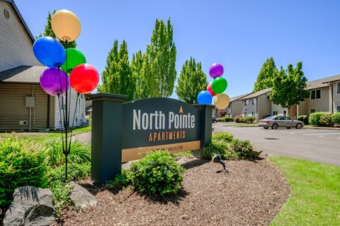 a sign that says north point apartments with balloons in front of it