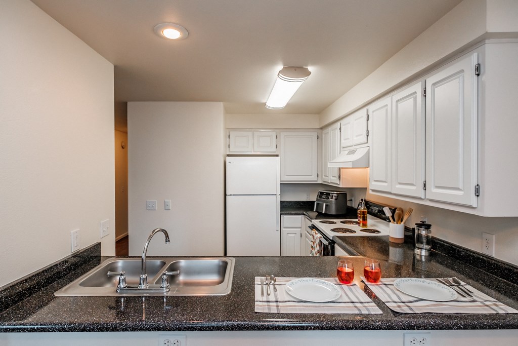 a kitchen with white cabinets and granite countertops