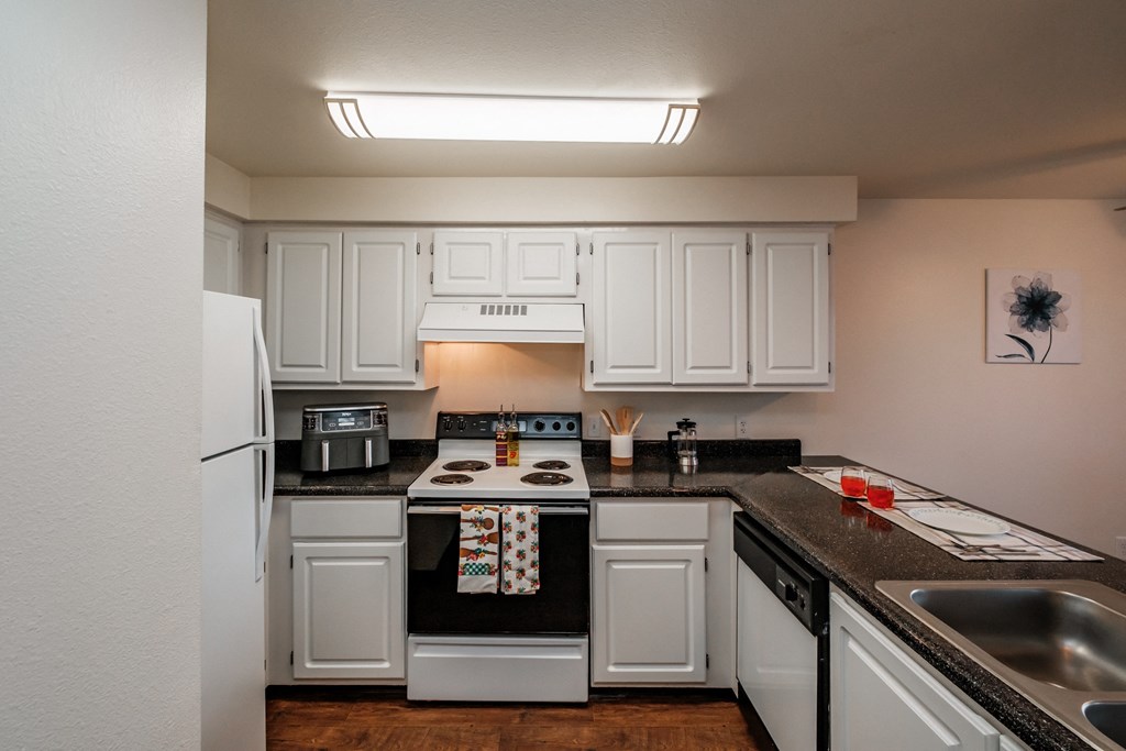 a kitchen with white cabinets and black countertops