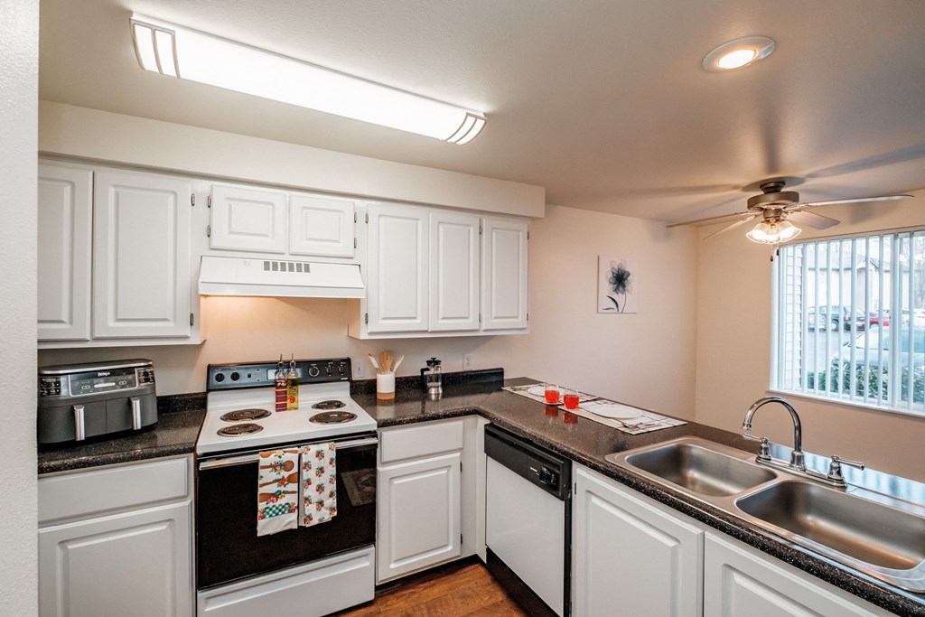 a kitchen with white cabinets and black countertops