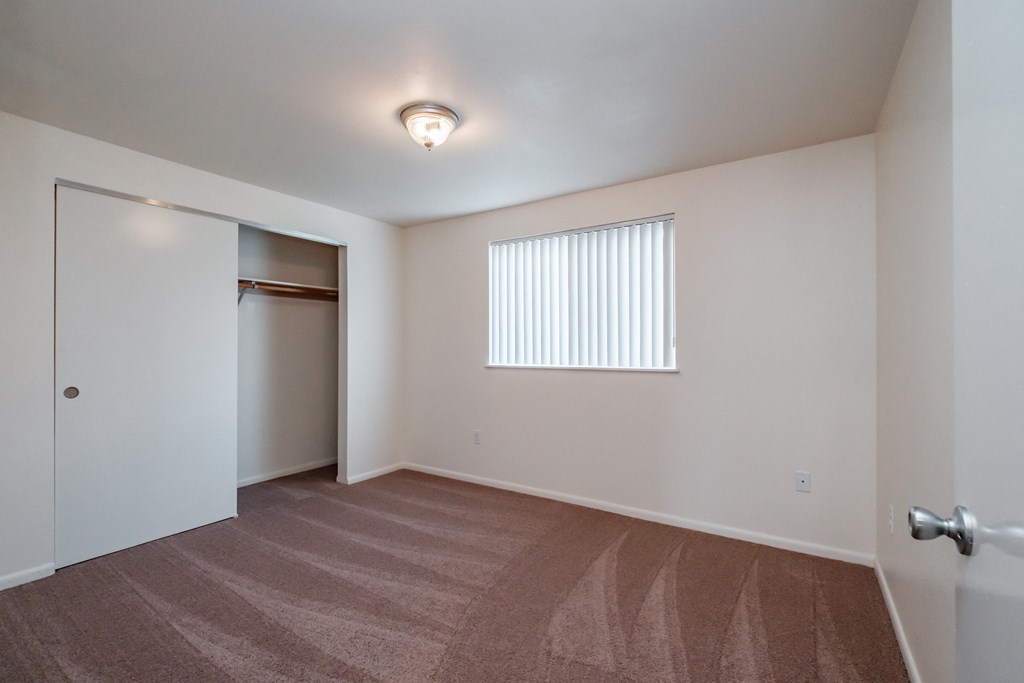 a bedroom with a door to a closet and a window