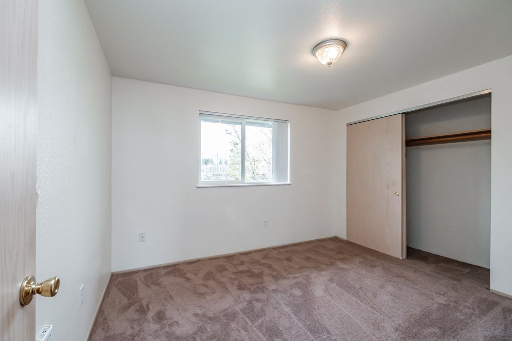 a bedroom with a large window and a closet