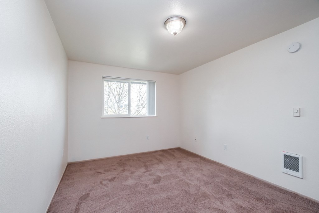 a bedroom with white walls and a window