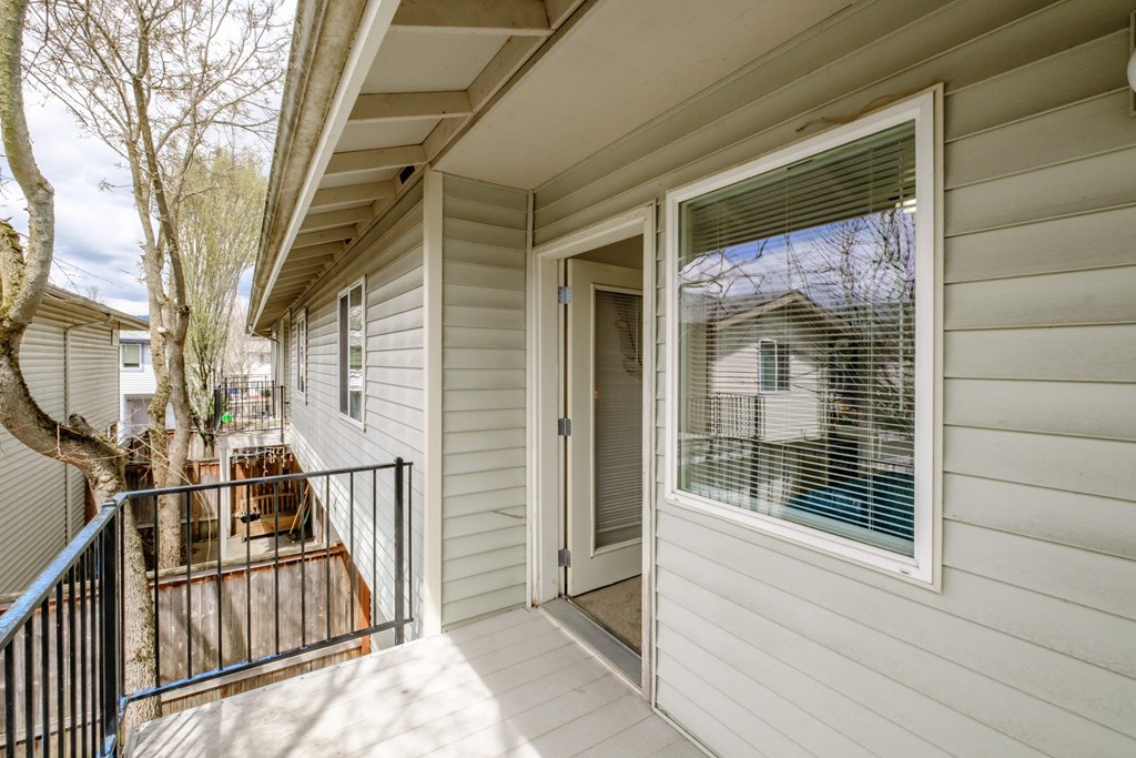 a front porch with a black railing and a white house in the background