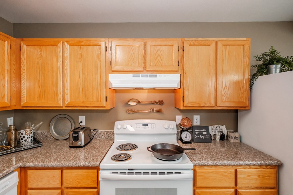 a kitchen with wooden cabinets and a white stove top oven