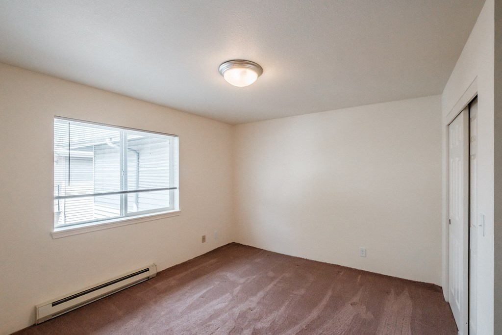 an empty bedroom with a large window and a closet