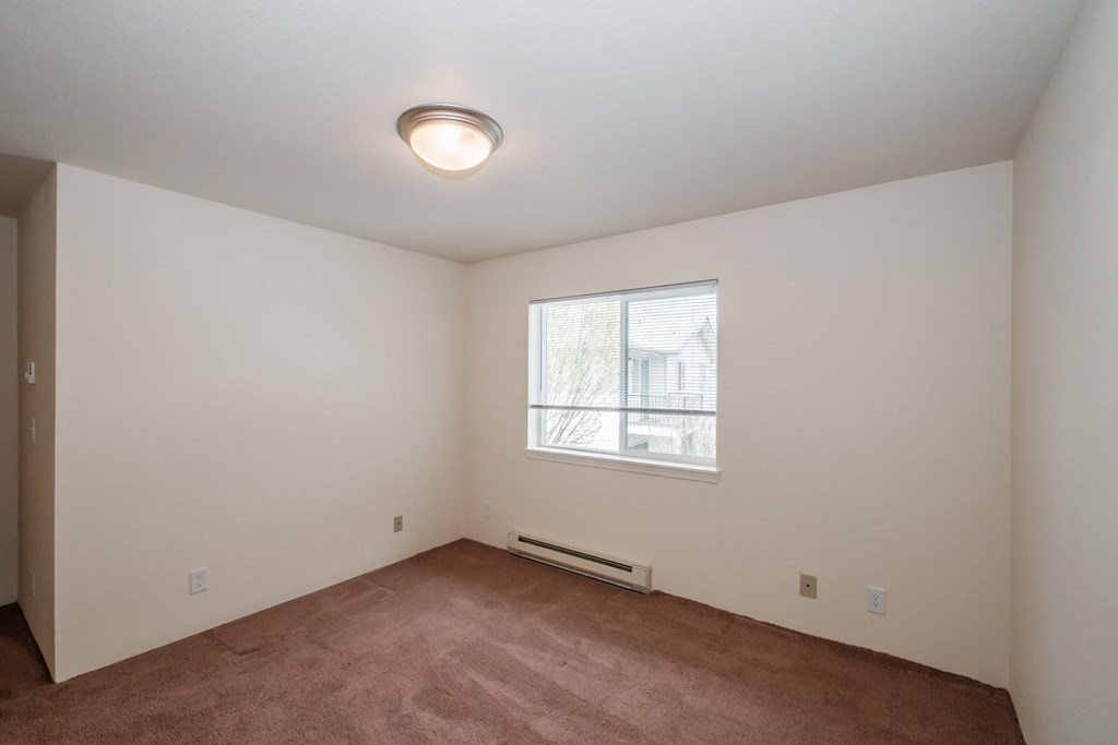 a bedroom with a large window and a carpeted floor