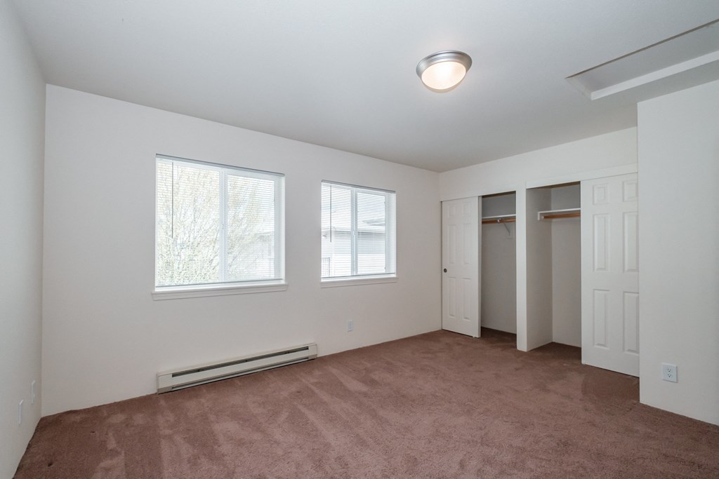 a bedroom with a carpeted floor and three windows