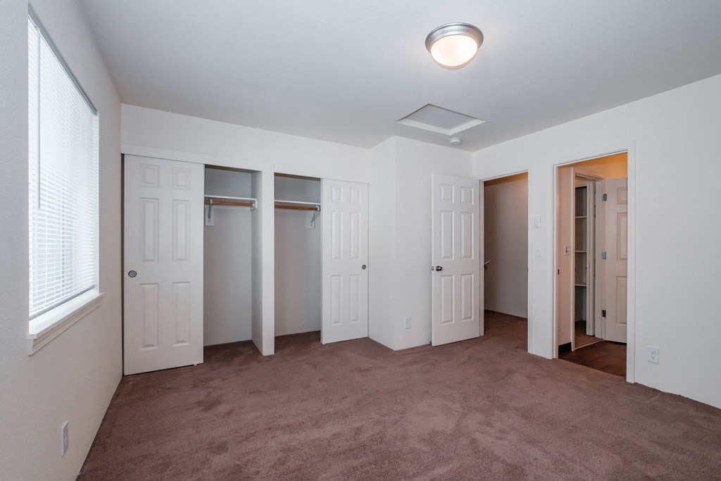 a bedroom with a carpeted floor and three closets