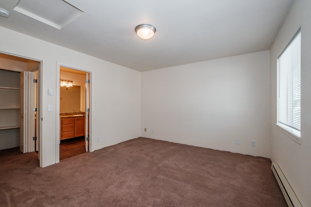 a bedroom with a carpeted floor and a door leading to a bathroom