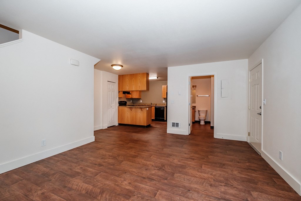 a living room with a hardwood floor and a kitchen in the background