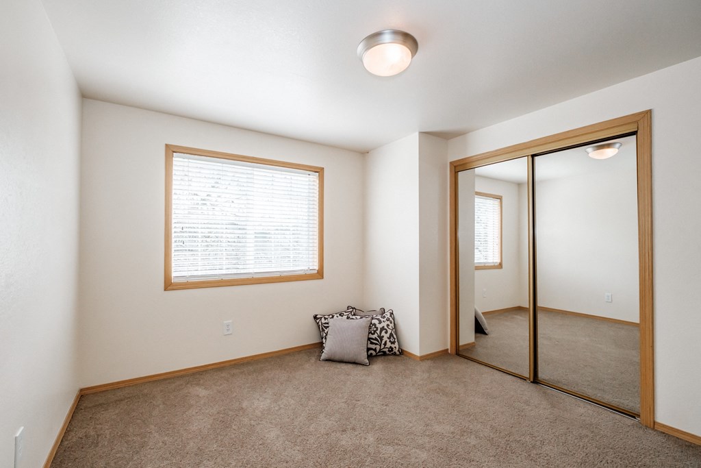a bedroom with carpeted floors and a large mirror