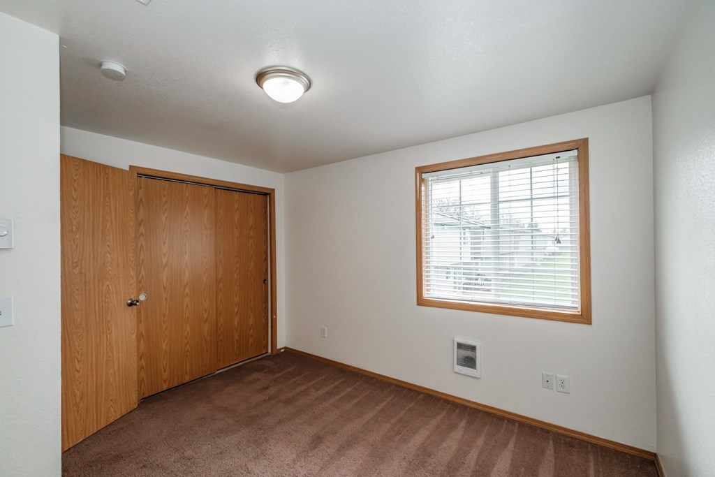 an empty bedroom with a large window and a wooden door