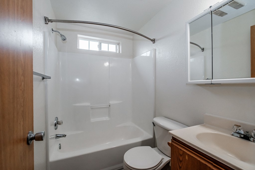 a bathroom with a white bathtub and toilet next to a sink and a mirror