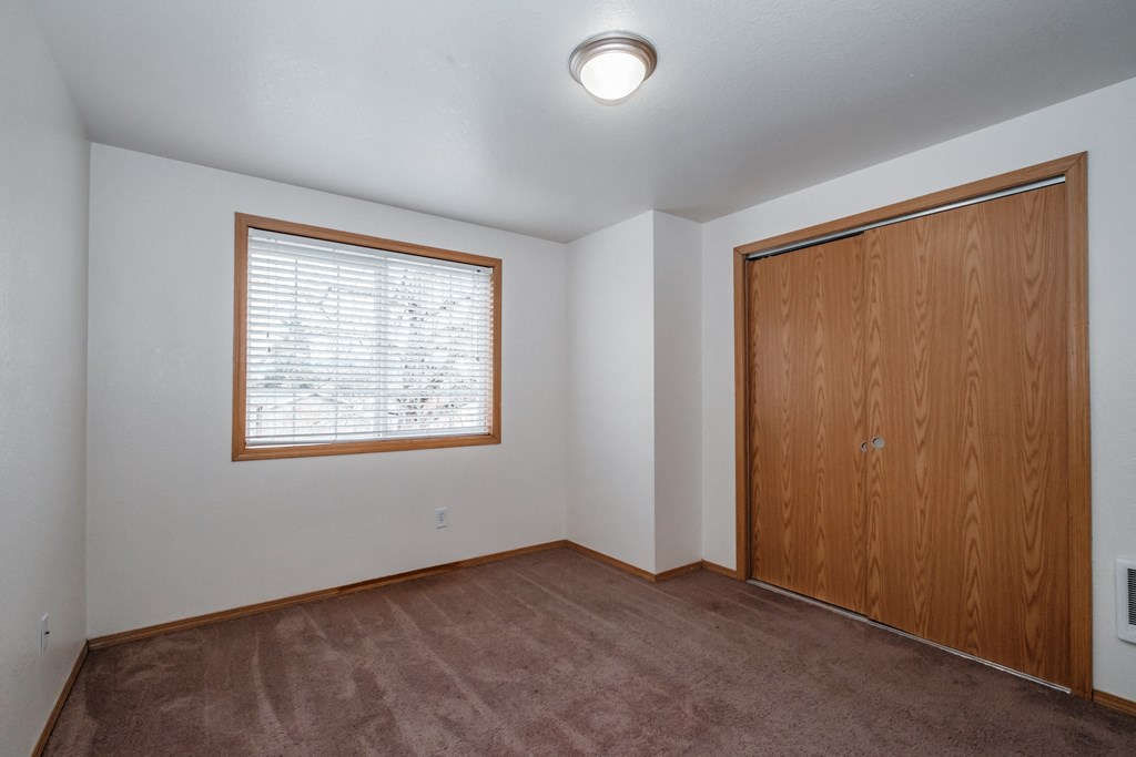 an empty bedroom with a large window and a wooden door