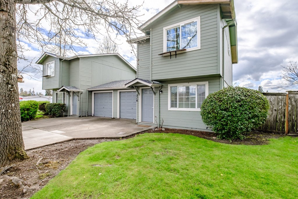 a gray house with a gray garage and a green lawn