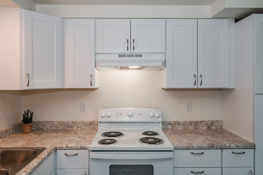 a kitchen with white cabinets and a white stove top oven